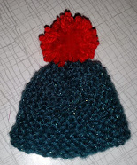 In Double Knit Glitter wool with a red pom-pom